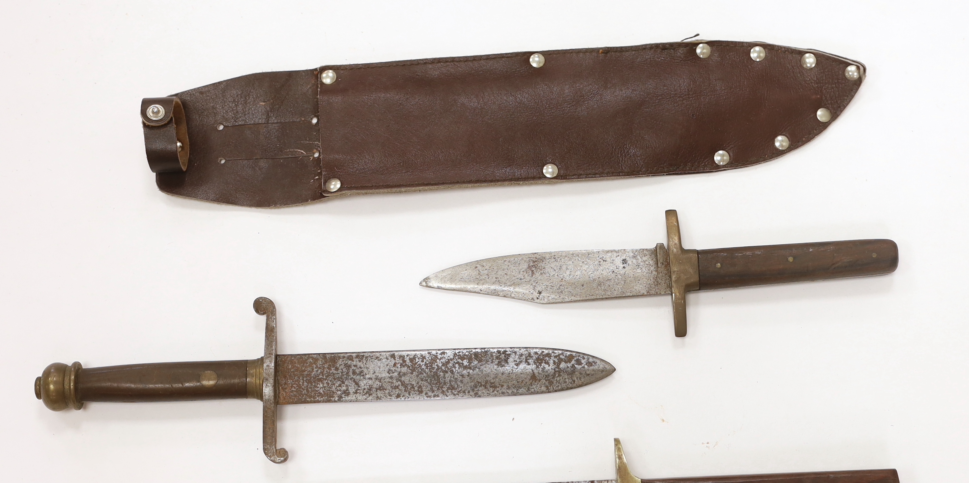 A Bowie knife with wooden grip, in a leather sleeve, blade etched with ‘Siege of The Alamo 1836 Col. Jim Bowie’s final stand’, blade 26.5cm, together with two smaller knife daggers (3)